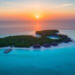 Vue aérienne d'une station balnéaire exclusive sur une île au coucher du soleil.