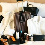 Mala de luxo com itens essenciais de viagem em uma cama macia.