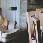 gray wing chair with throw pillows beside white door