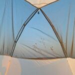 A white tent with a black bag on top of it