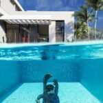 a person swimming in a pool with a house in the background