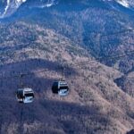white and black cable car over green mountains during daytime