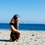 a man doing a handstand on a beach