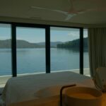 a bedroom with a large window overlooking a body of water