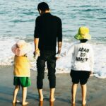 a man and two children are standing on the beach