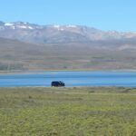 a car is parked on the side of a road near a lake
