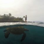a man standing on a rock in the water with a large fish