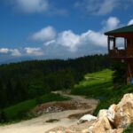 Wooden house overlooks beautiful mountains and sky.