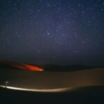 a person standing in the middle of a desert at night