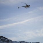 A helicopter flying over a snow covered mountain