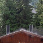 a cabin in the woods with smoke coming out of the chimneys