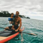 2 men riding on orange kayak on sea during daytime