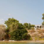 Mykonos vs Paros for Low-Key Privacy and Helipad Access a house sitting on top of a hill next to a body of water