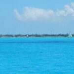 Sailboat on bright blue ocean with distant island