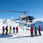 Helicopter landing on a snowy mountain for heli-skiing.
