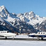 PC-12 and King Air on alpine runway with mountains.